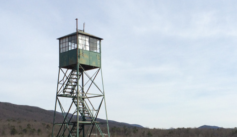 green fire lookout tower among mountains